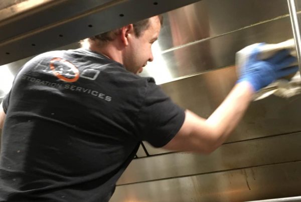 Image of Halo employee wiping down an exhaust system in a commercial kitchen