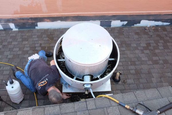 Halo employee scraping kitchen exhaust grease from rooftop in Las Colinas, Irving, TX