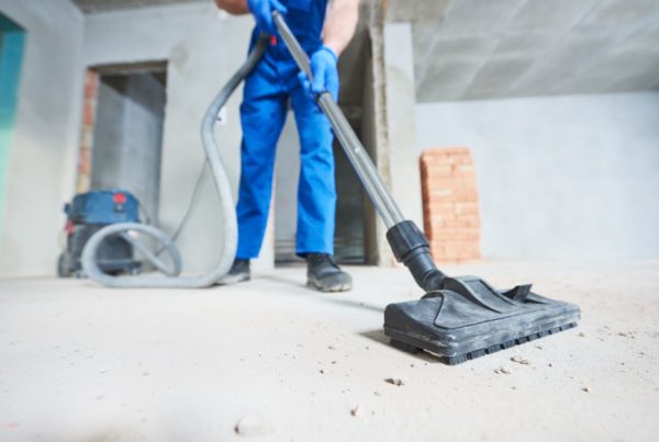 Technician using a shop vacuum to clean up construction debris